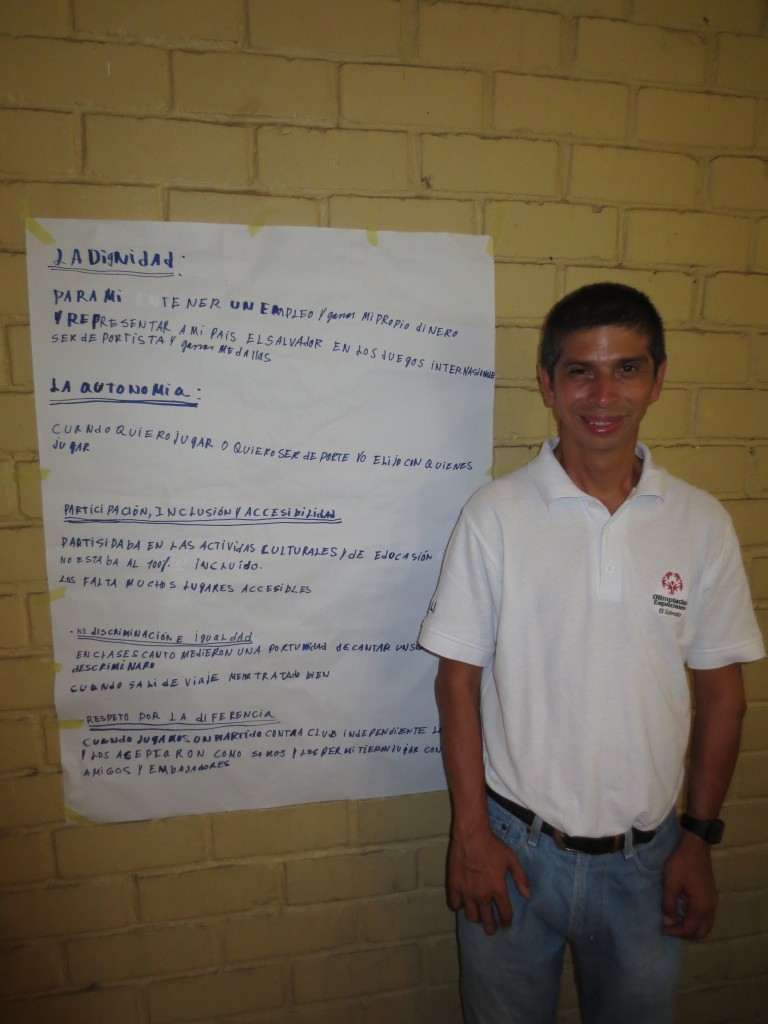 A workshop participant poses in front of a chart with the human rights principles written on it.